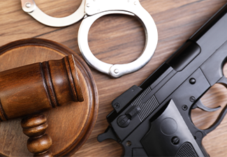 Judge's gavel, handcuffs and gun on wooden table, flat lay