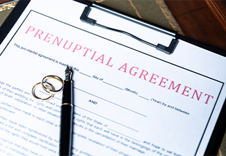 Close-up of a prenuptial agreement form with wedding rings and a fountain pen