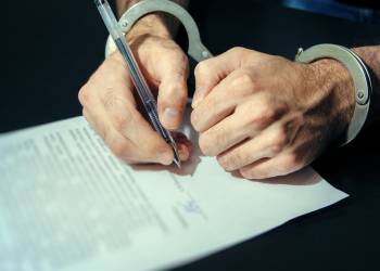 Man in handcuff signing plea agreement