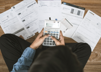 Man sitting on the floor stressed and calculating expense