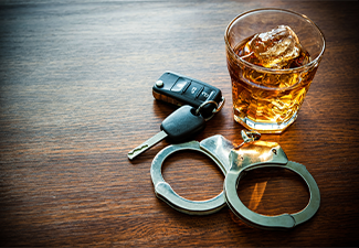 Handcuff car key and whiskey on glass