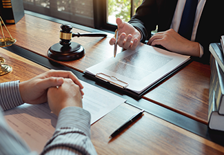 Lawyer working with client discussing contract papers with brass scale