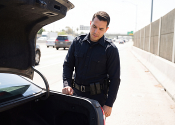 Police officer searching car trunk