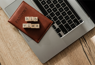 H1B visa wooden blocks on passport and laptop, symbolizing U.S. work permit