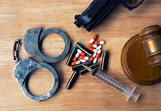 Drugs handcuffs gun and gavel on the table