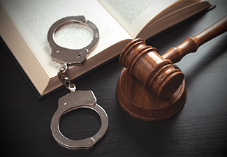 Handcuffs and wooden gavel on the table