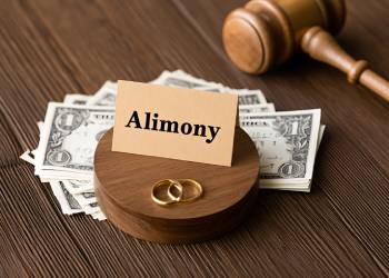 Alimony concept with judge gavel, money, and wedding rings