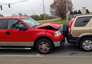 Rear-end vehicle collision involving red truck with bent hood and brown suv