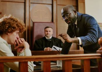 A lawyer questions a nervous man in a courtroom before a judge