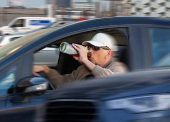 Man driving car while drinking alcohol
