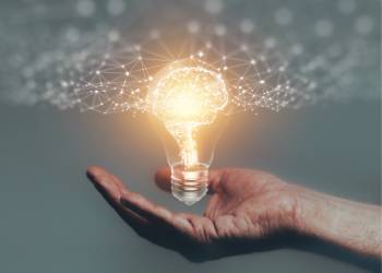 Hands holding bulb with glowing brain