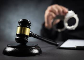 Judge's gavel and handcuffs in hand