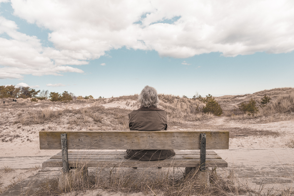 Elderly Woman Sitting on a Bench Looking into a Distance