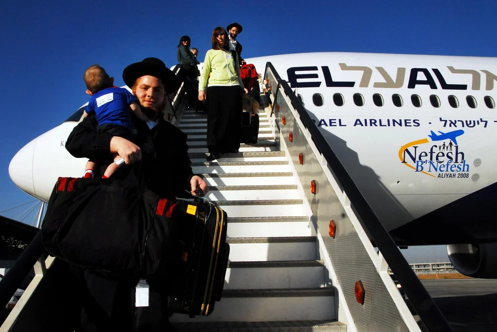 Orthodox Jewish man holding baby leaving a plane