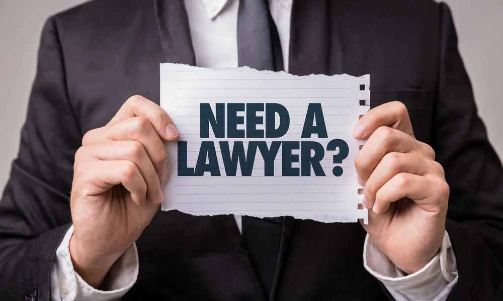 Man holding a page saying Need a Lawyer