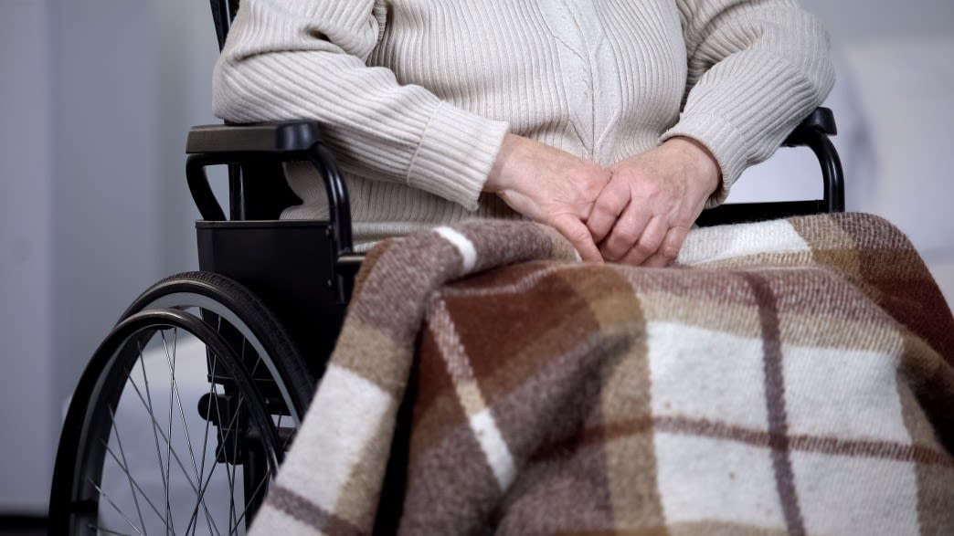 Old woman on wheelchair with blanket on her legs