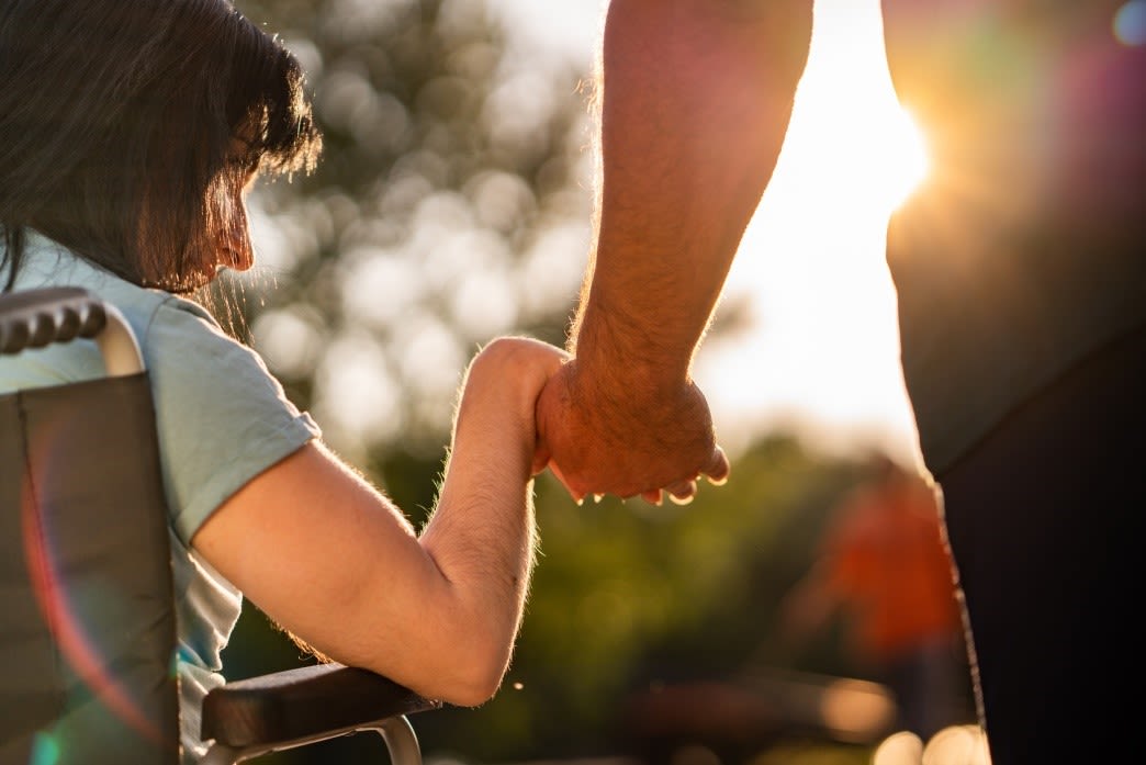 Husband holding hands with wife on wheelchair