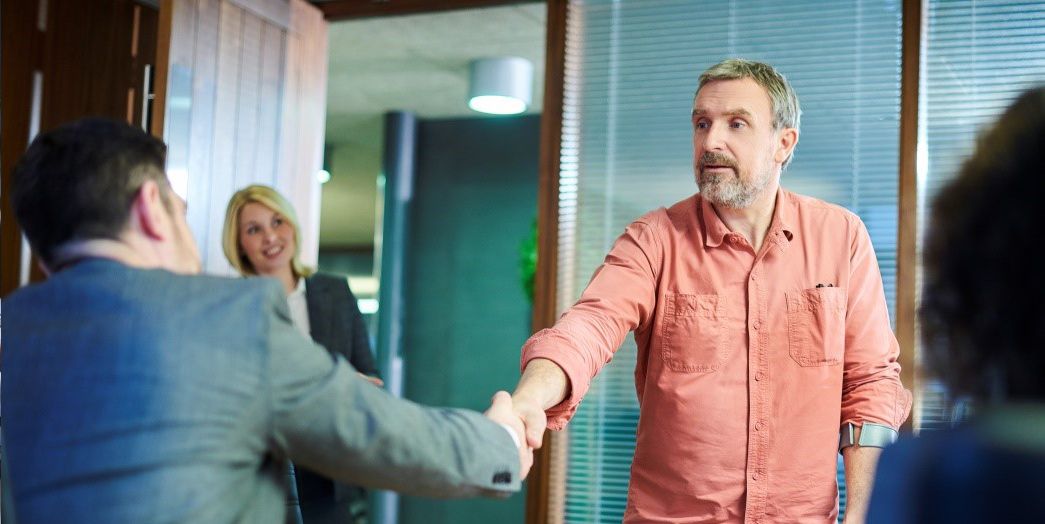 Attorney shaking hands with client with two women looking at them