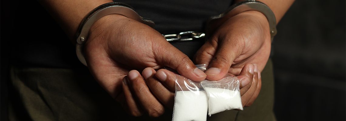 Handcuffed man with drugs in hand