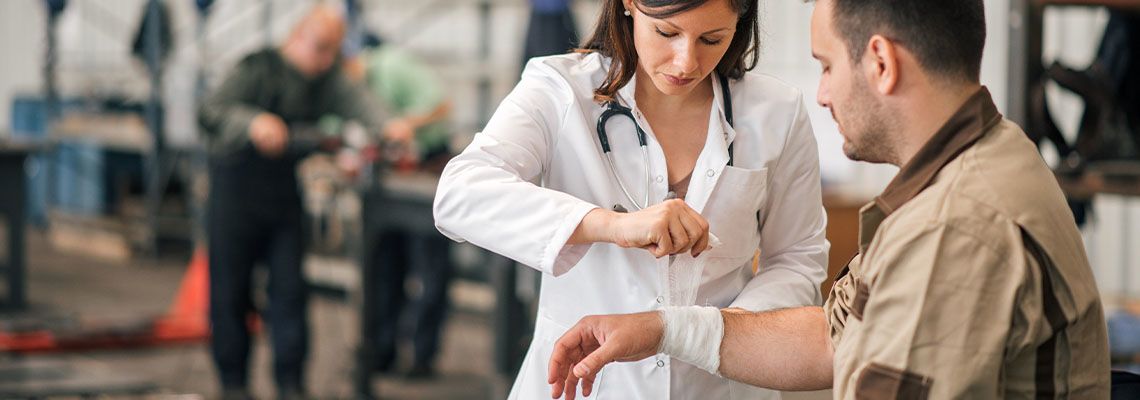 Female Doctor applying bandage to factory worker