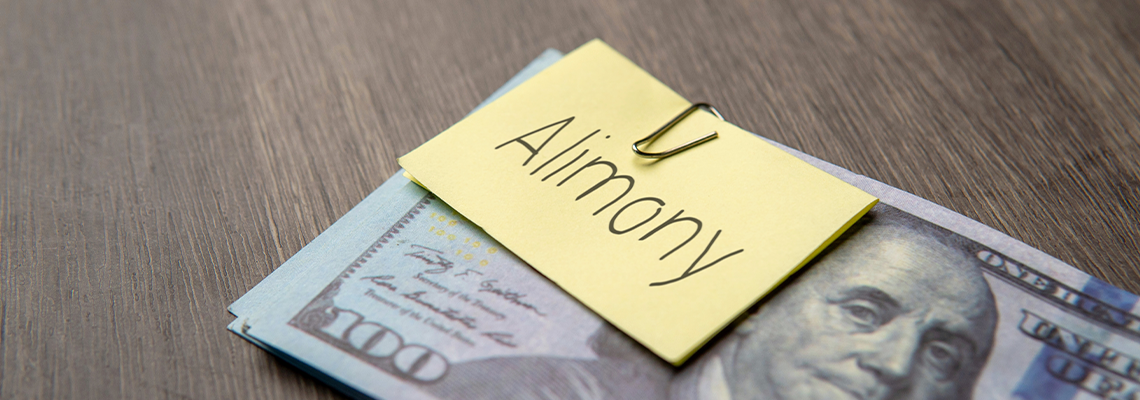 US dollar banknote clipped with a yellow note labeled alimony