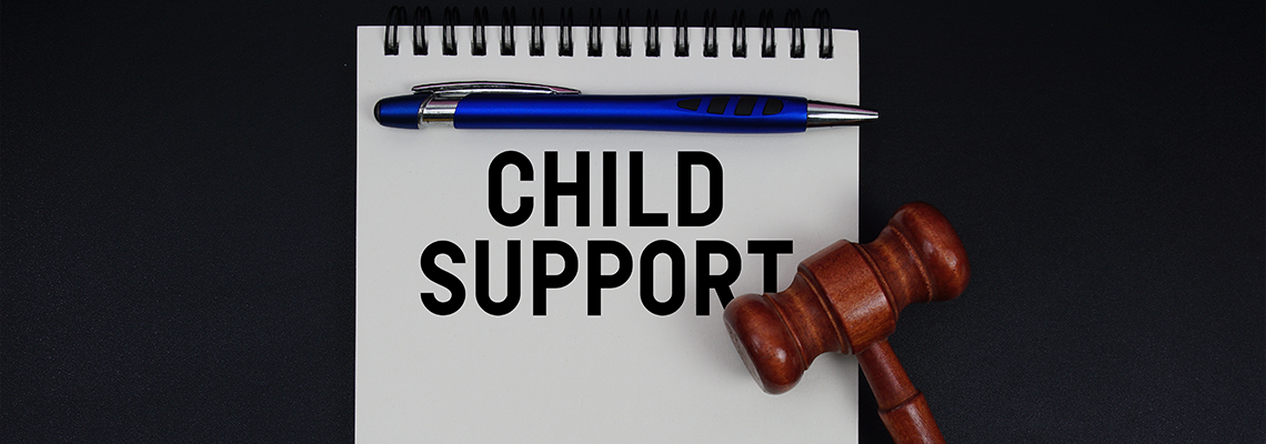 Child Support text written on notepad with gavel on black background