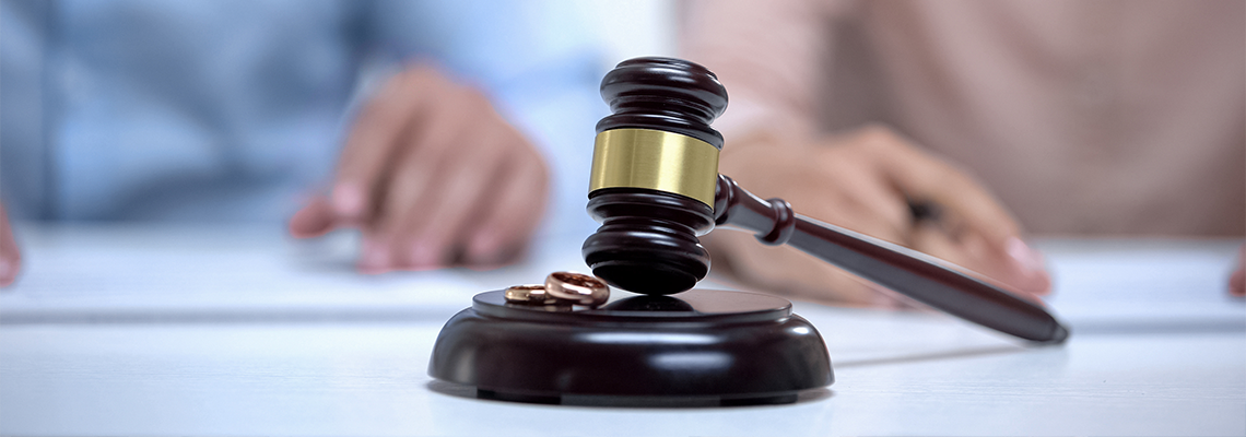 Marriage rings and a gavel closeup with a couple in the background
