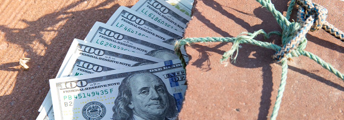 US Dollars Tied and Pressed by Brick