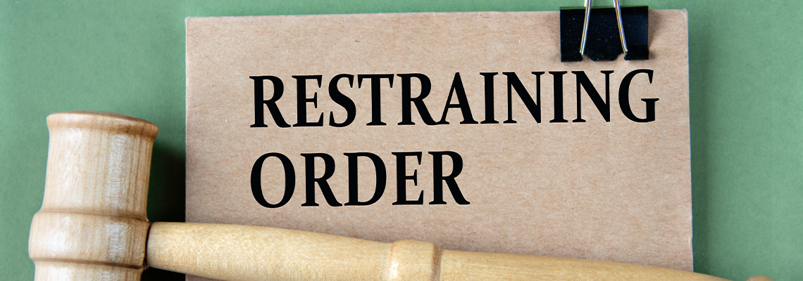 RESTRAINING ORDER - words on brown paper with a judge's gavel