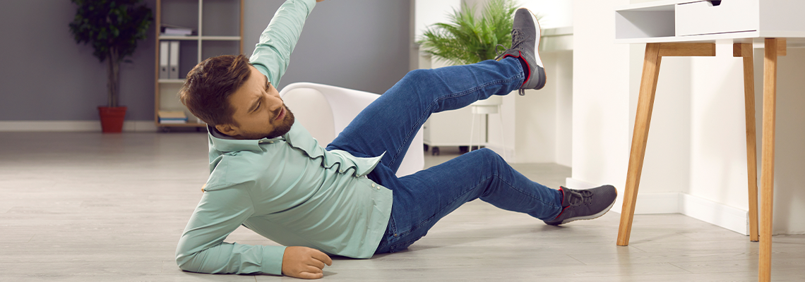 Man with unshaven bristles falling down to the floor and injuring his arm