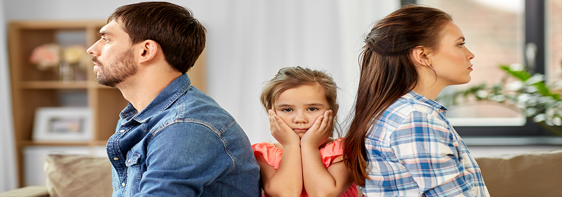 Small child with head in hands sitting between two adults
