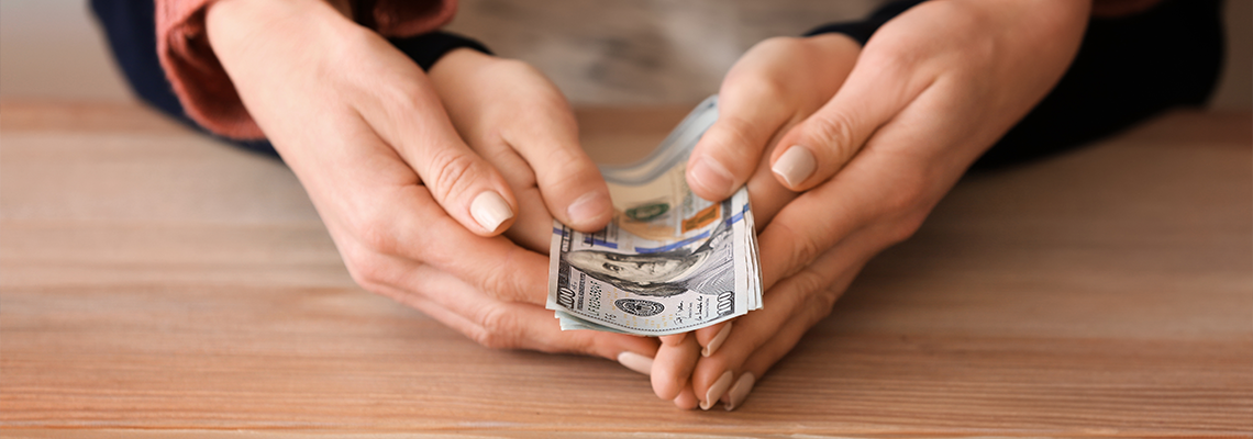 Woman with his son holding dollar banknotes on wooden table