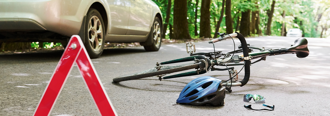 Bicycle and silver colored car accident on the road at forest at daytime