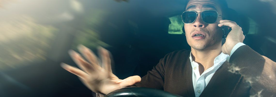 man with sunglasses is talking on the phone while driving
