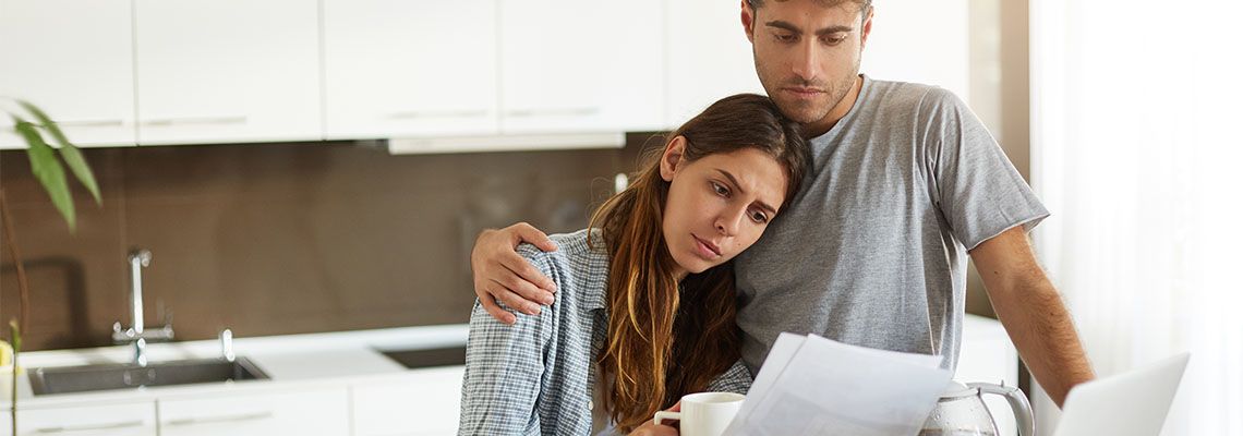 Husband and Wife looking at paper with worried expression