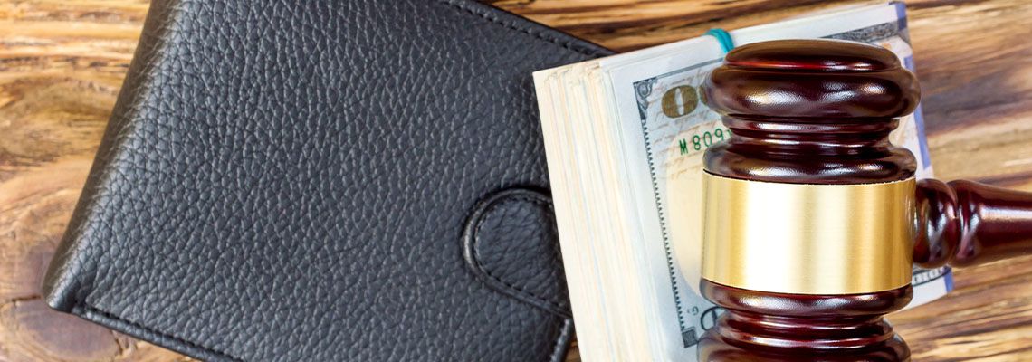 Gavel with folded dollars and wallet on the table