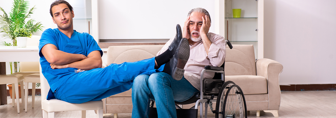 Old man in wheel-chair and young bad caregiver indoors