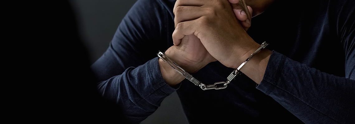 Criminal man with handcuffs in interrogation room