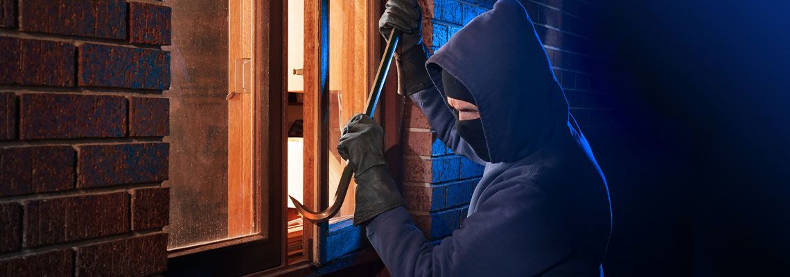 Burglar Using Crowbar To Break Into a House