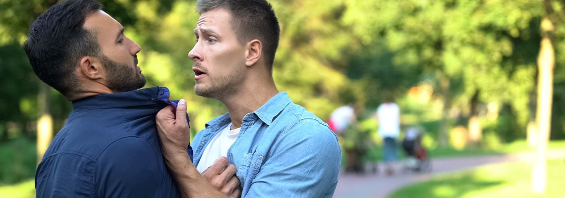 Angry man assaulting another man outdoors