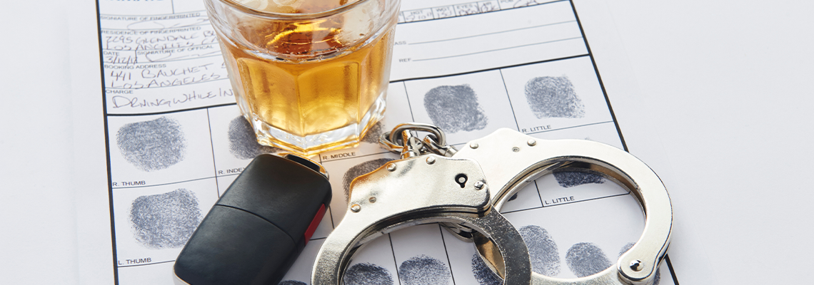Handcuffs with fingerprints keys and glass of alcohol on ice