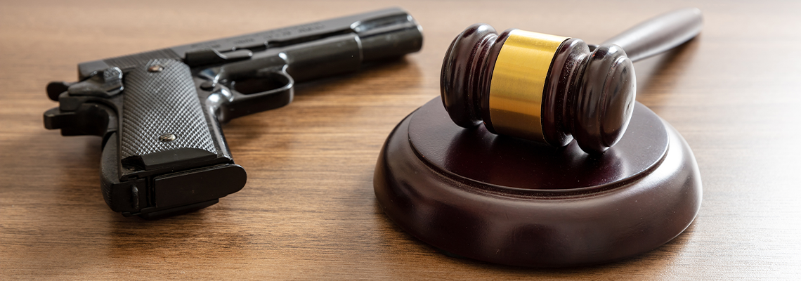 Judge gavel and handgun on table, close up