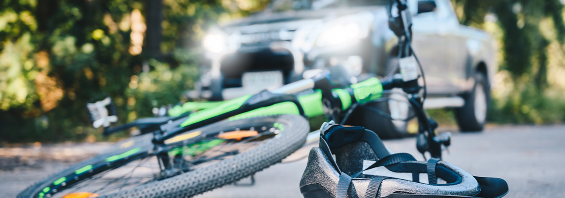 Close-up of a bicycling helmet fallen on the asphalt next to a bicycle