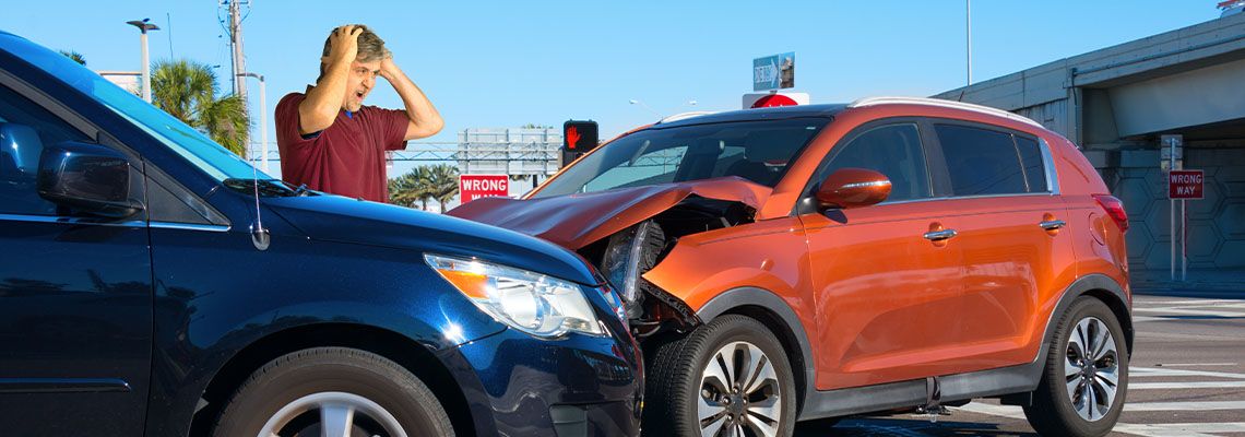 Upset man looking at damages after car crash