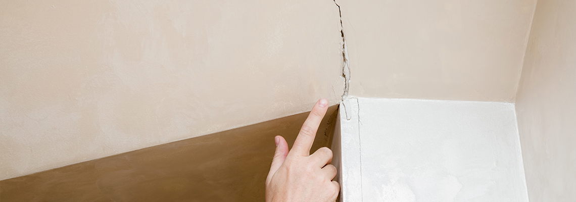 Man's Hand Finger Pointing to The Cracked Wall in House