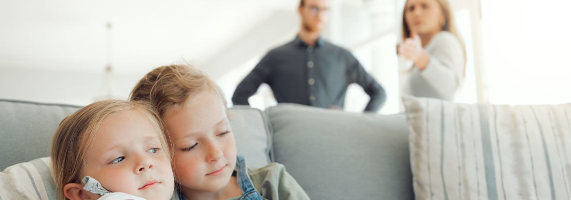Sad children with parents discuss child custody in background