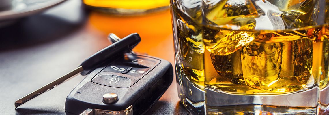 Car keys and glass of alcohol on table