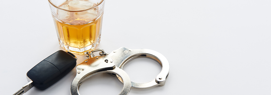 Handcuffs, keys and glass of alcohol on ice with copy space