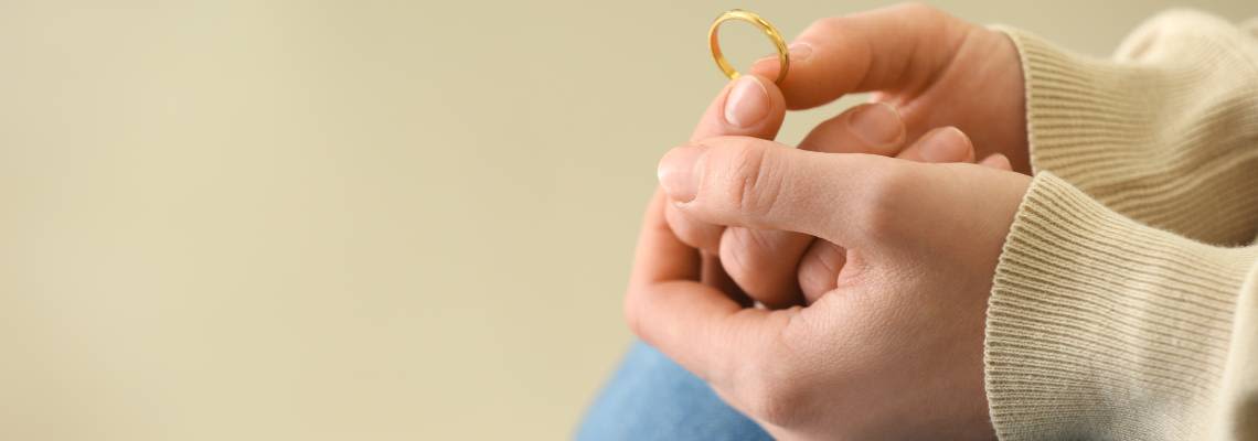 Women holding wedding ring in hand considering divorce