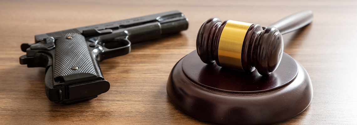 Judge gavel and handgun on table